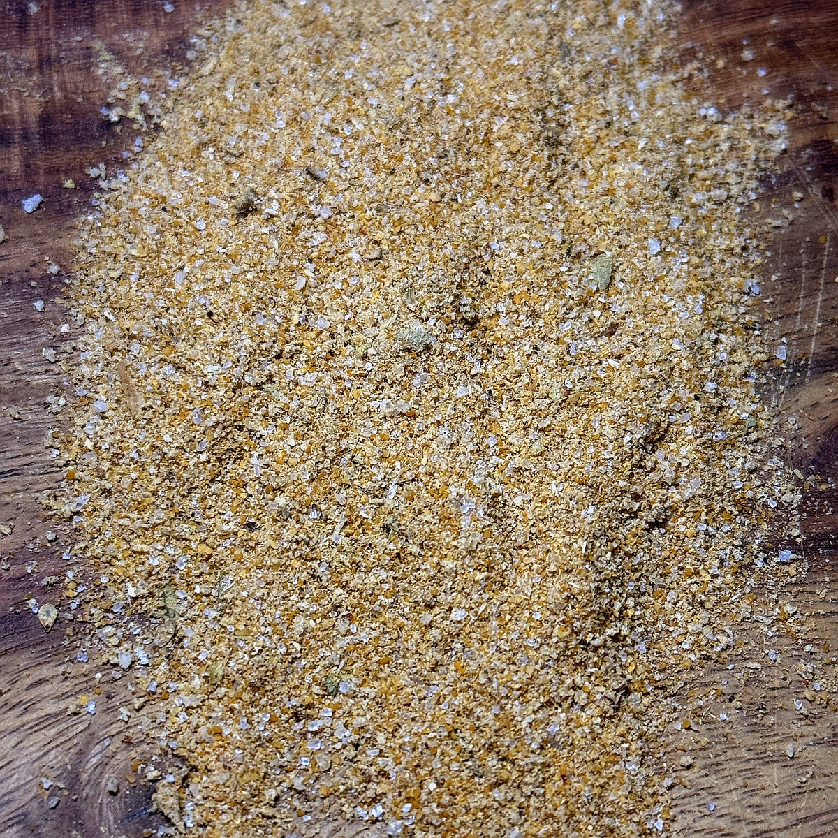 A close-up view of Spicy Mustard Seasoning on a wooden surface, showcasing its vibrant golden color and texture.