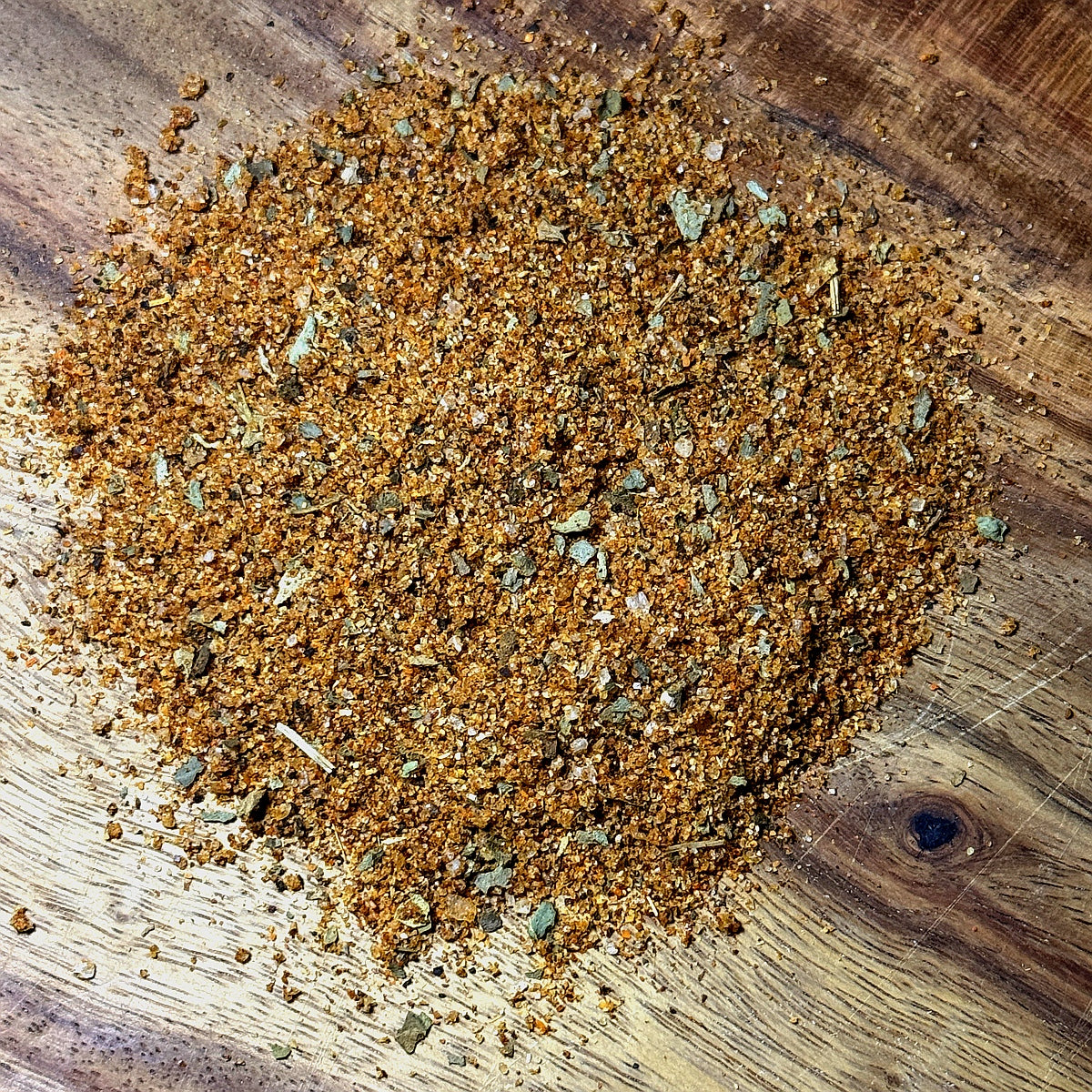 Chili Lime Basil Seasoning spilled on a wooden surface, showcasing its vibrant blend of spices.