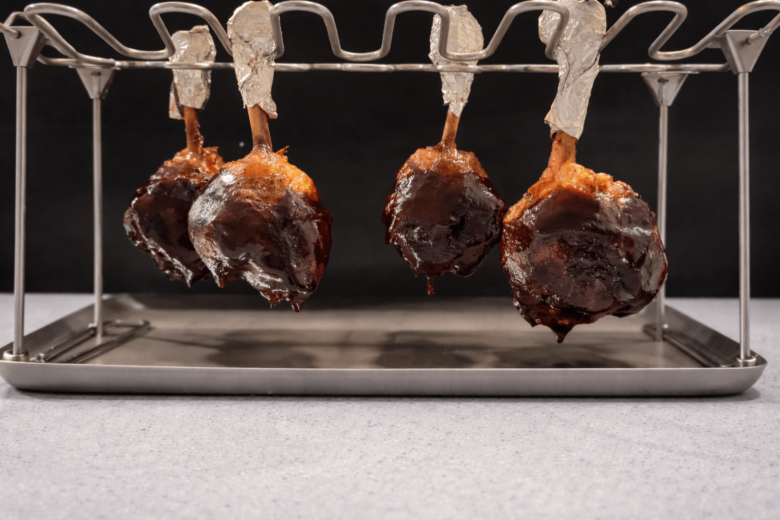 Dried blood sausages hanging on a metal rack with a dark background