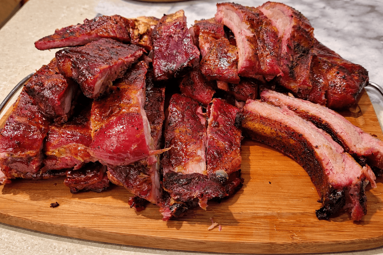 Barbecue ribs on a wooden cutting board with a marble background