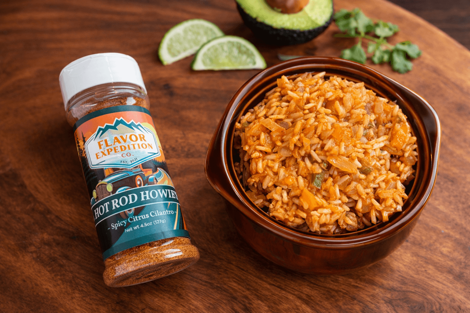 Bottle of Flavor Expedition Hot Rod Howie seasoning next to a bowl of rice on a wooden surface.