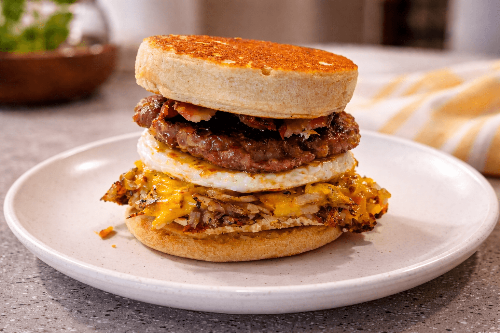 Stacked breakfast sandwich on a plate with a blurred background