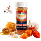A bottle of Flavor Expedition Co. 'Volcanic Sunset' seasoning stands on a white background surrounded by food props including honeycomb, honey, a honey dipper, garlic cloves, red and orange habanero peppers, and chili peppers. [pack-1]