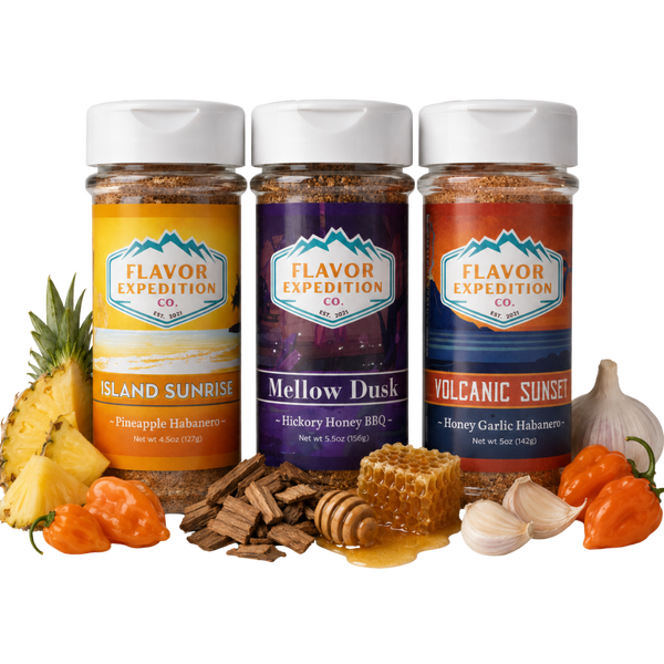 Three jars of Flavor Expedition Co. spices with ingredients like pineapple, garlic, and peppers on a white background.