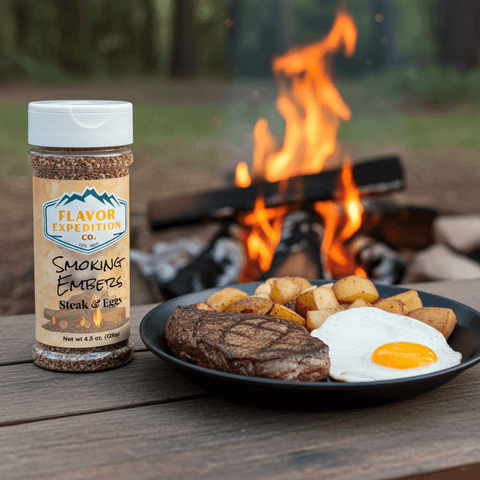 Bottle of 'Flavor Expedition Co. Smoking Embers' seasoning next to a plate of food by a campfire.
