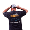 Man wearing a Wildly Delicious T-Shirt from Flavor Expedition Co. showcasing a vibrant logo.