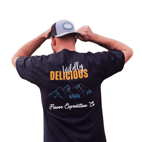 Man wearing a Wildly Delicious T-Shirt from Flavor Expedition Co. showcasing a vibrant logo.