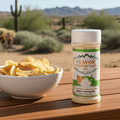 Bowl of chips with a jar of Flavor Expedition Co. seasoning on a wooden surface with desert landscape in the background